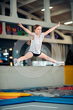 Girl jumping high in striped tights on trampoline.