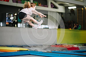 Girl jumping high in striped tights on trampoline.