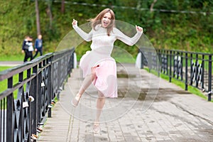 Girl jumping for joy on a bridge over the river