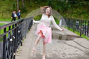 Girl jumping for joy on a bridge over the river