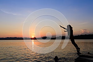 Girl jumping in a lake during sunset