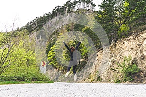 Girl jumping in the middle of the road in a national park Durmitor, Montenegro. Red Head jump for happiness and freedom