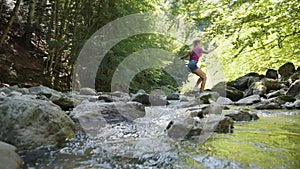 Girl jumping over pristine creek in the woods