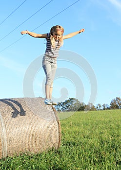 Girl jumping from package of hay