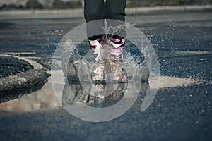 Girl jumping into puddle, water splash on road