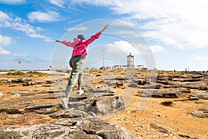 Girl jumping on rocks with arms outstretched in Carvoeiro cape