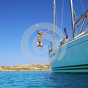 Girl jumping in sea off boat