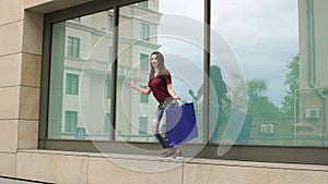 Girl jumping with shopping bags near shopping mall