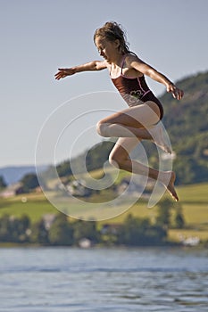 Girl jumping to lake, Norway photo