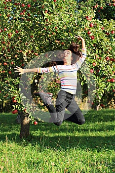 Girl jumping under apple tree