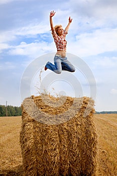 Girl jumping up on straw roll