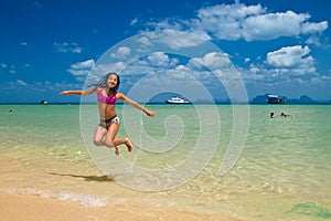 Girl jumping in the water at the beach of the Koh Ngai island Th