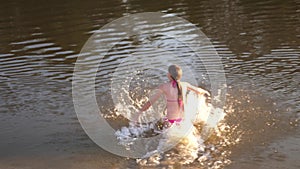 Girl jumping into water on summer hot day smiling and laughing. Happy teenage girl bathing in river