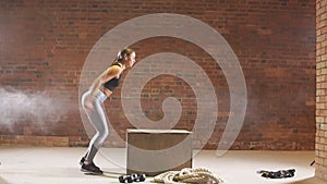 Girl jumping into wooden boxes in a training. Crossfit workout. Slow motion