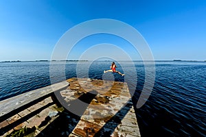 Girl jumping with a wooden bridge in the water in the summer.Toning