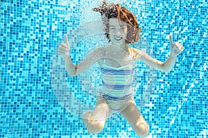 Girl jumps, dives and swims in pool underwater, happy active child has fun under water, kid sport o