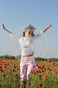 Girl jumps over poppy field