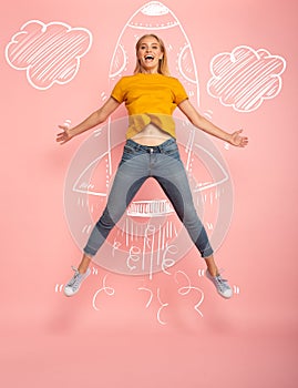 Girl jumps on pink background ready to fly like a rocket. Concept of freedom, energy and vitality photo