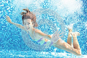 Girl jumps and swims in pool underwater, child has fun in water