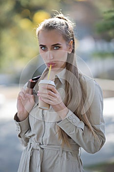 Girl in a jumpsuit similar to the uniform in public Park with a Cup of fast food coffee