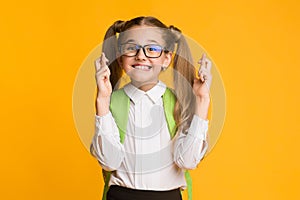 Girl Keeping Fingers Crossed For Luck Posing On Yellow Background