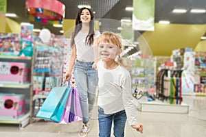 Girl keeping hand of mom and running forwardn in toy store