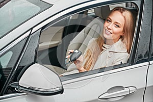 Girl with keys in hands sitting in driver's seat of car.