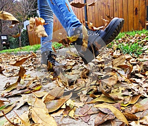 Girl kicking dry leaves on the street