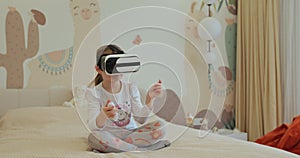 Girl kid child schoolgirl playing online video game in 3D world metaverse using virtual reality helmet at home.