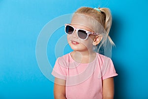 Girl kid in sunglasses isolated on blue background. Fashion cute pretty child