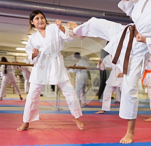 Girl in kimono blocking kick during karate training