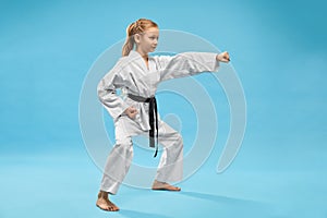 Girl in kimono standing in stance and punching with hand.