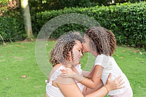 A girl kisses her mother on the forehead in the open air