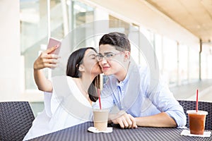 Girl Kissing Boyfriend On Cheek While Taking Selfportrait In Mall