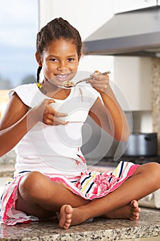 Girl In Kitchen Eating Bowl Of Breakfast Cereal