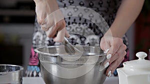 The girl in the kitchen interferes with the milk mass from the dough whisk