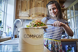 Girl In Kitchen Making Compost Scraping Vegetable Leftovers Into Bin