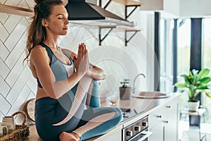 Girl in the kitchen meditating practicing yoga.