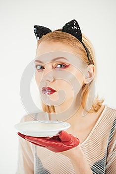 Girl in kitten ears and red gloves with yoghurt isolated on white. cat woman lick milk from plate. Food and drink