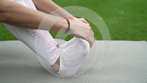 Girl kneading toes while sitting on a sports mat