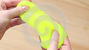 Girl kneads yellow slime against the background of a table