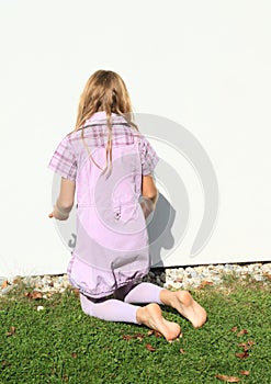 Girl kneeing in front white wall photo