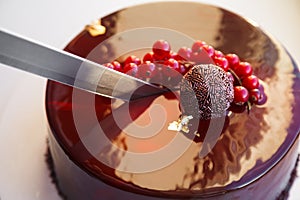 Girl knife ombre marble mousse cake decorated with red mirror glaze and berries.