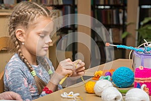 The girl knits embroidery in the school library