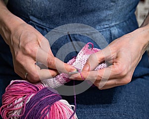 Girl knits on needles with pink yarn