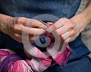 Girl knits on needles with pink yarn