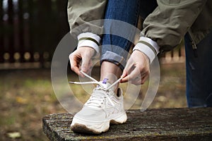 Girl knits shoelaces on sports sneakers. Outdoor sports