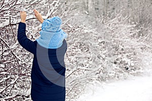 Girl in a knitted blue scarf, and cap stands