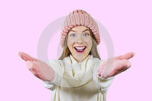 Girl in a knitted hat and gloves is smiling and holding out her hands in greeting on an isolated background