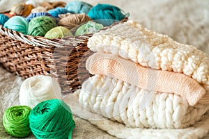 Girl knitting at home. Multi-colored balls of knitting thread in the basket. and a knitted white scarf